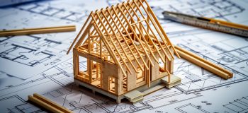 Generated by OkiDokiBot.com Wooden frame house model under construction on blueprints building project concept